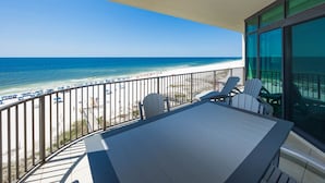 Ein Balkon mit Blick auf den Strand, einem Tisch und zwei Stühlen.