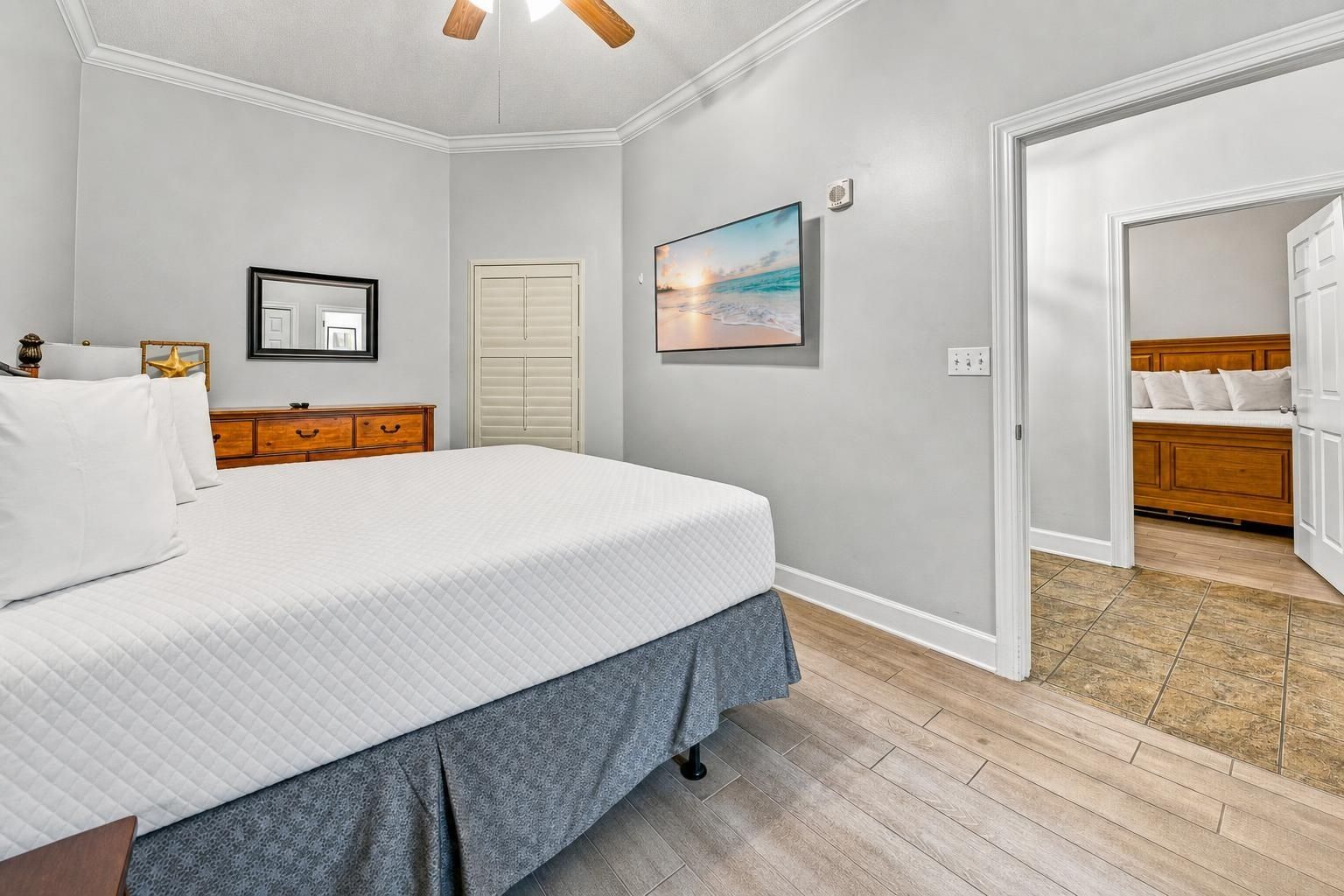 Een slaapkamer met een bed, een kaptafel, een spiegel, een deur en een schilderij aan de muur.
