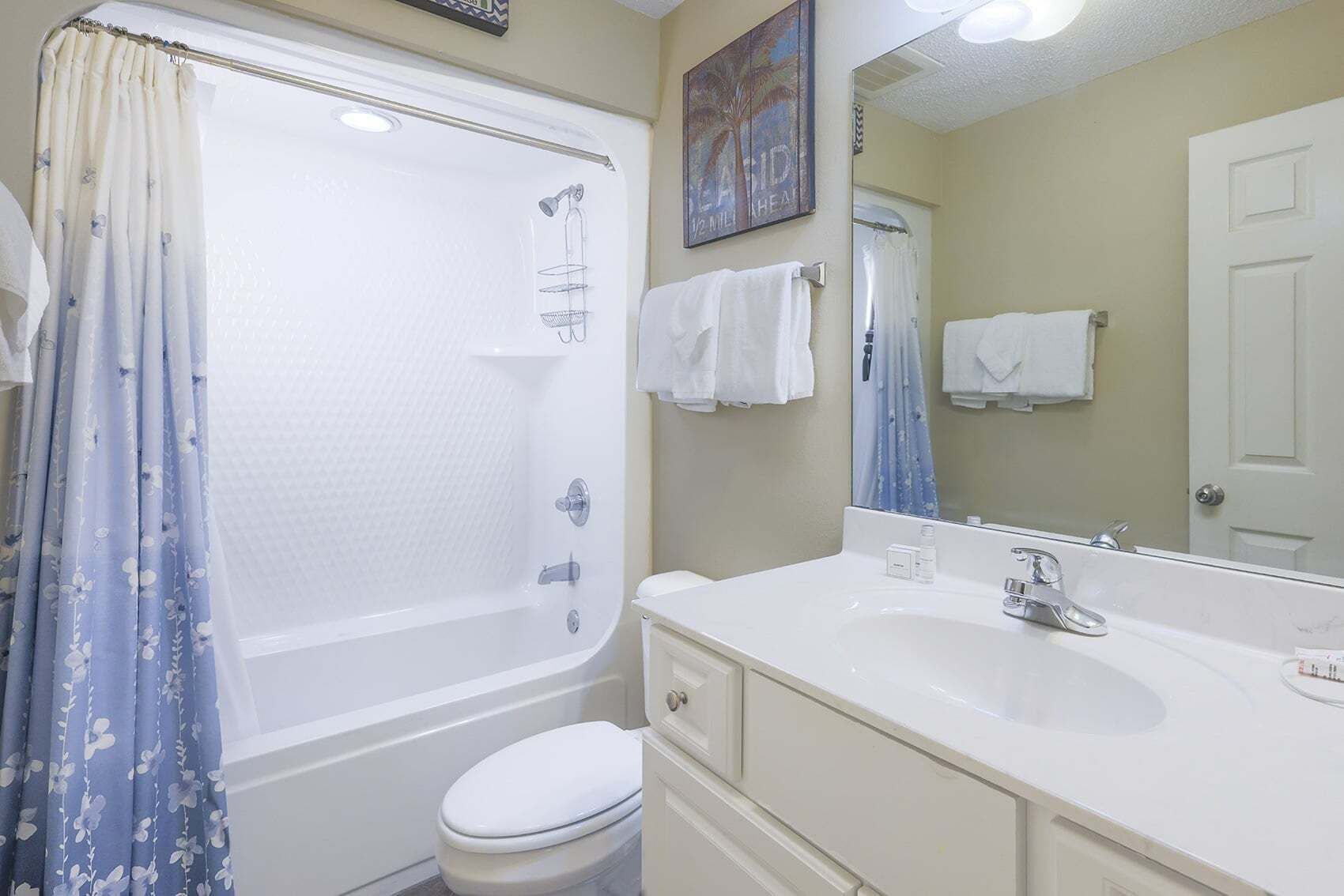 A bathroom with a bathtub, toilet, sink, and a mirror.