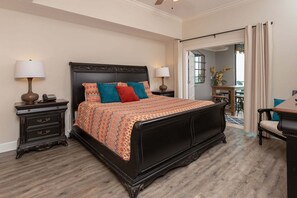 A bedroom with a large bed, two bedside tables, a dresser, and a view of the balcony. - Phoenix West 2203 3 Bedroom Condo (Orange Beach)