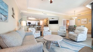 Ein Wohnzimmer mit einer Couch, Sesseln, einem Tisch und einem Fernseher.