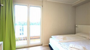 A bedroom with a bed, a sliding glass door, and a view of the outside. - Bendorf Hotel by Belvilla Double Room With Balcony (Bendorf)
