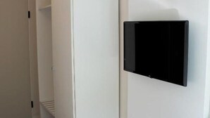 A room with a white wardrobe, a flat-screen TV mounted on the wall, and a wooden floor. - Bendorf Hotel by Belvilla Double Room With Balcony (Bendorf)