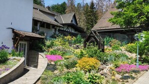 Een traditioneel gebouw in Europese stijl, met een hellend dak, een stenen pad en een tuin vol kleurrijke bloemen.