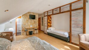 Een slaapkamer met een bed, een bureau, een stoel, een televisie en een kledingkast.