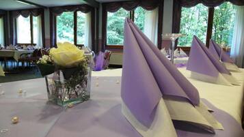 A banquet hall with tables set for a formal event, featuring purple napkins and a centerpiece with a yellow flower.