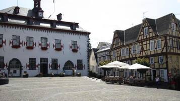 A cobblestone square with historic buildings, a clock tower, and outdoor seating.