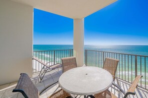 A balcony with a table and chairs, overlooking a beach and ocean. - The Oasis 1907 Formerly Phoenix West Ii 1907 3 Bedroom Condo (Orange Beach)