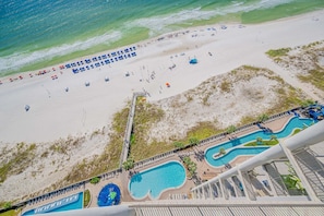 An aerial view of a beach with a swimming pool and lounge chairs. - The Oasis 1907 Formerly Phoenix West Ii 1907 3 Bedroom Condo (Orange Beach)