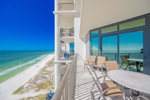 A balcony with a view of the beach and ocean, outdoor seating, and a table. - The Oasis 1907 Formerly Phoenix West Ii 1907 3 Bedroom Condo (Orange Beach)