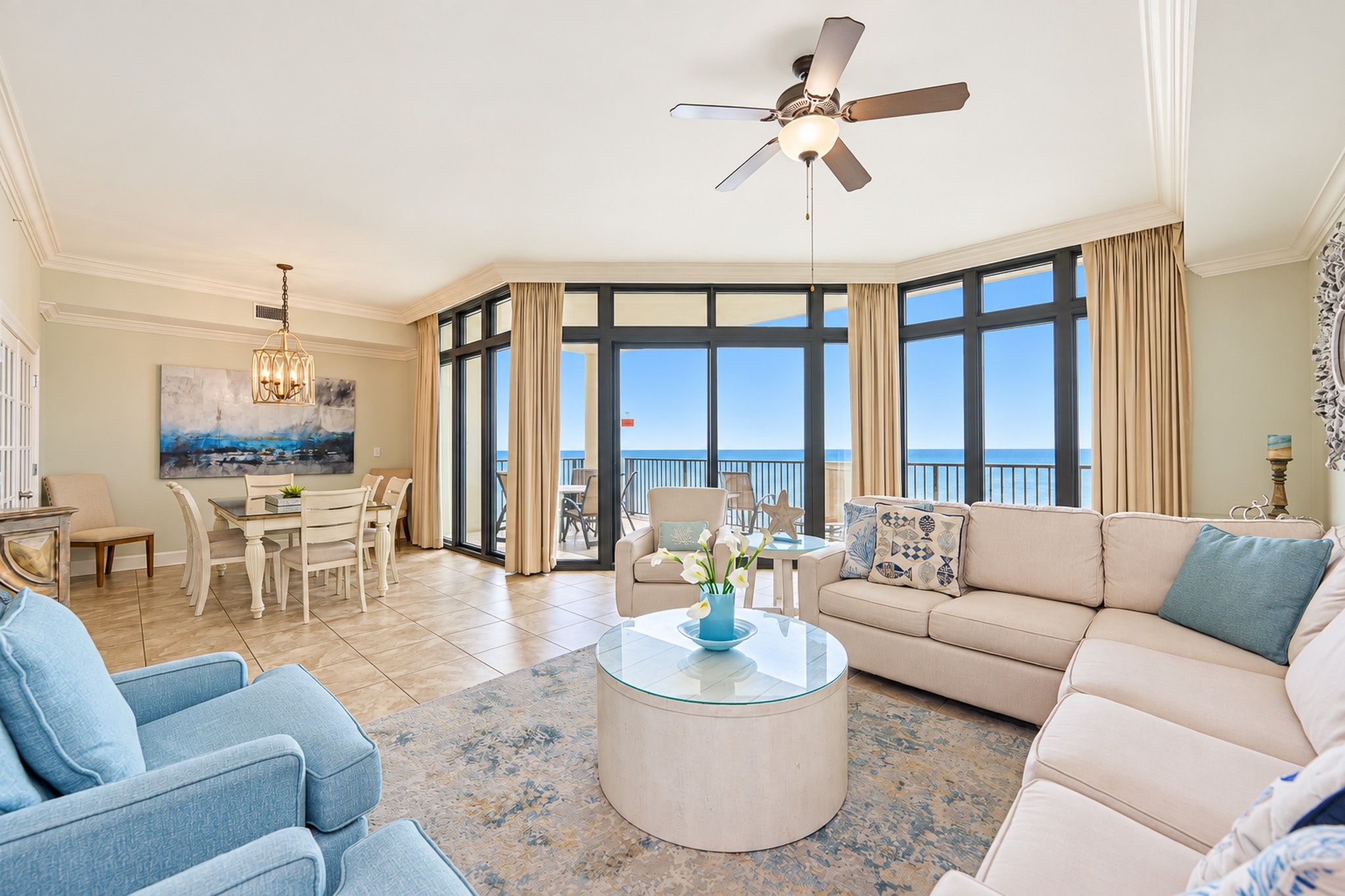 A spacious living room with a large window, a ceiling fan, and a dining area with a table and chairs.