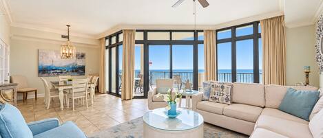 A spacious living room with a large window, a ceiling fan, and a dining area with a table and chairs.