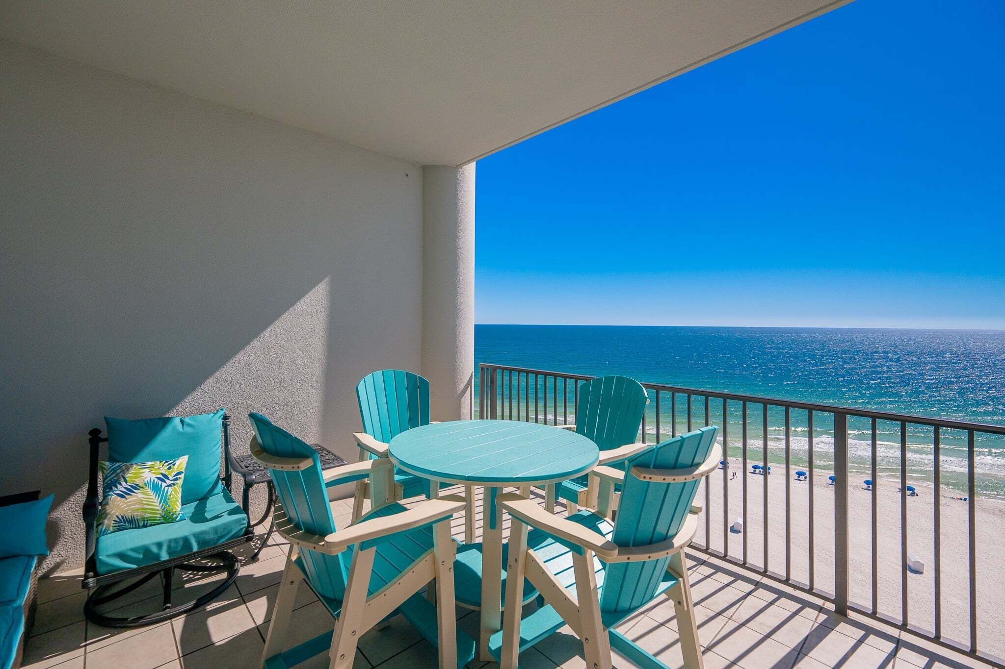 Un balcon avec vue sur l’océan, une table ronde et quatre chaises.
