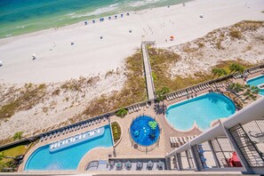 An aerial view of a resort with a beach, a pool area, and a lifeguard tower. - The Oasis 1010 Formerly Phoenix West Ii 1010 3 Bedroom Condo (Orange Beach)