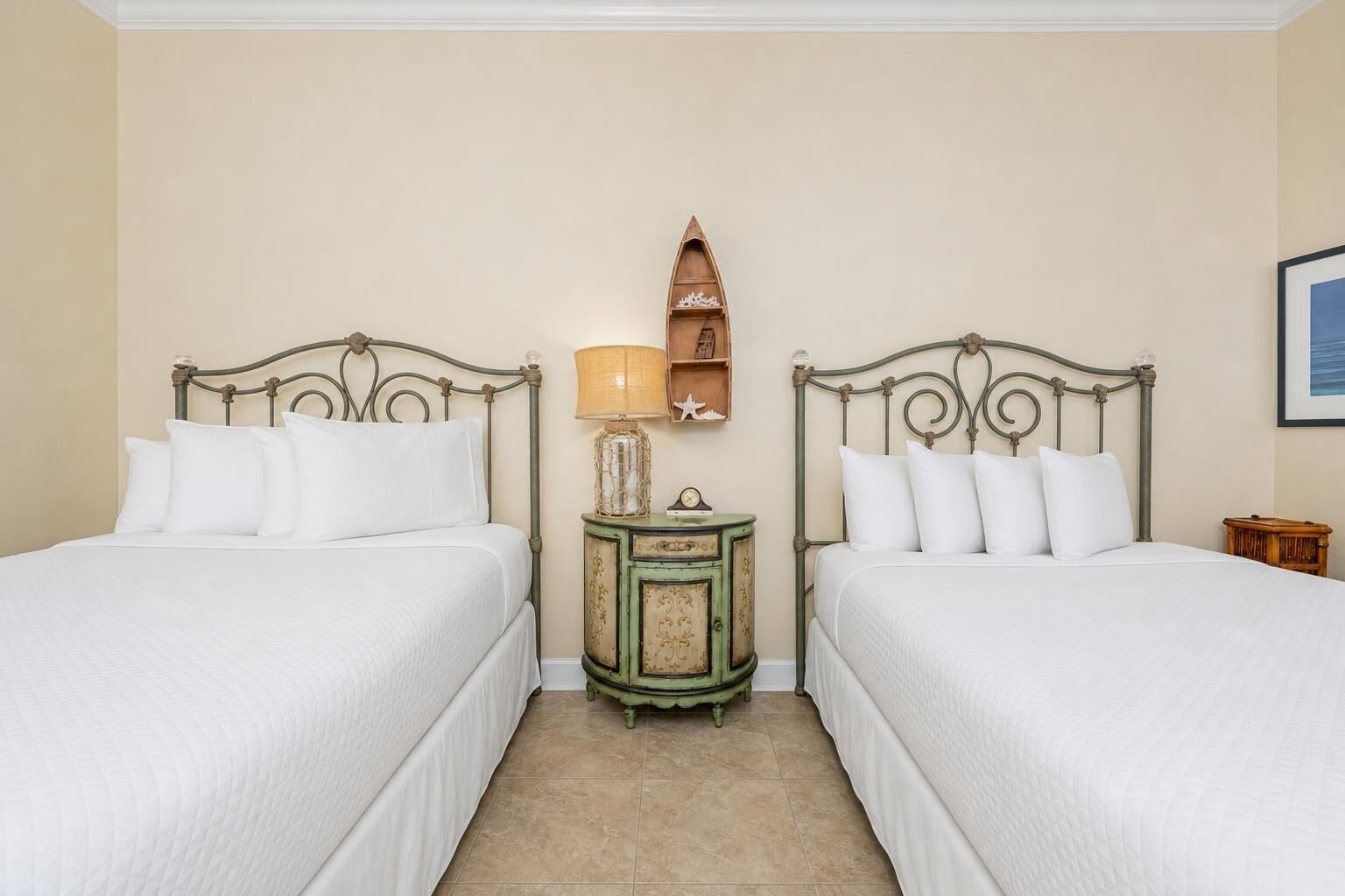 Una habitación con dos camas, una mesita de noche con lámpara y una estantería decorada.