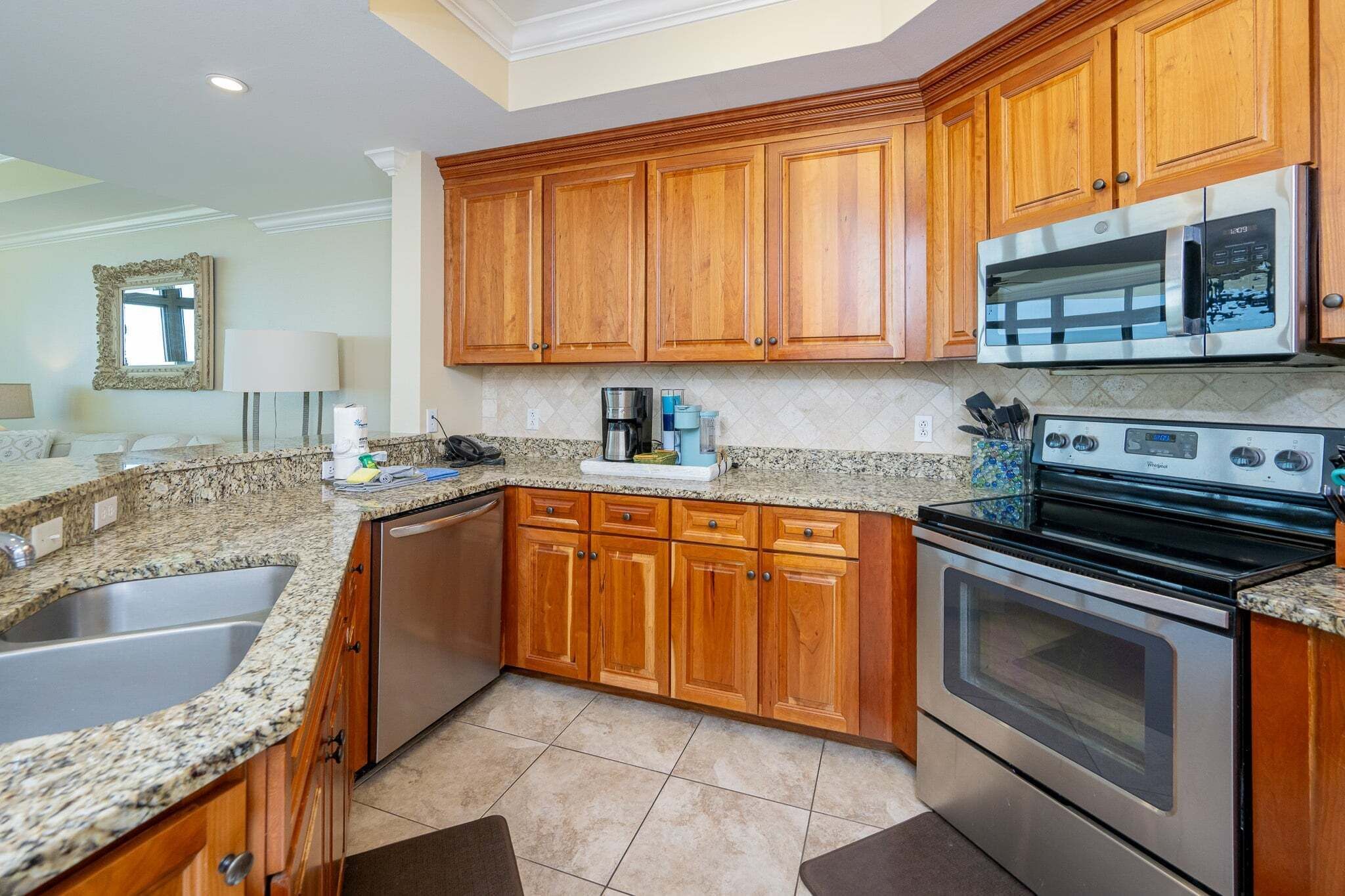A kitchen with wooden cabinets, granite countertops, stainless steel appliances, and a built-in oven.