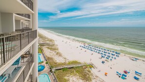 A beachfront hotel with a pool, beach umbrellas, and a view of the ocean. - The Oasis 1203 Formerly Phoenix West Ii 1203 3 Bedroom Condo (Orange Beach)