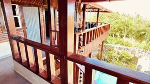 A wooden balcony with a view of a swimming pool and greenery. - Charming Villa in Cabrera With Ocean View (Cabrera)