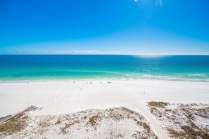 Ein Strand mit blauem Himmel, sandigem Ufer und weiter Ferne.