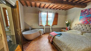 Quarto com cama grande, banheira e janela com cortinas.