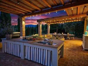 An outdoor kitchen area with a built-in sink, cooking pots, and a dining setup under a pergola. - Large and beautiful villa with swimming pool in the Tuscan hills (Fucecchio)