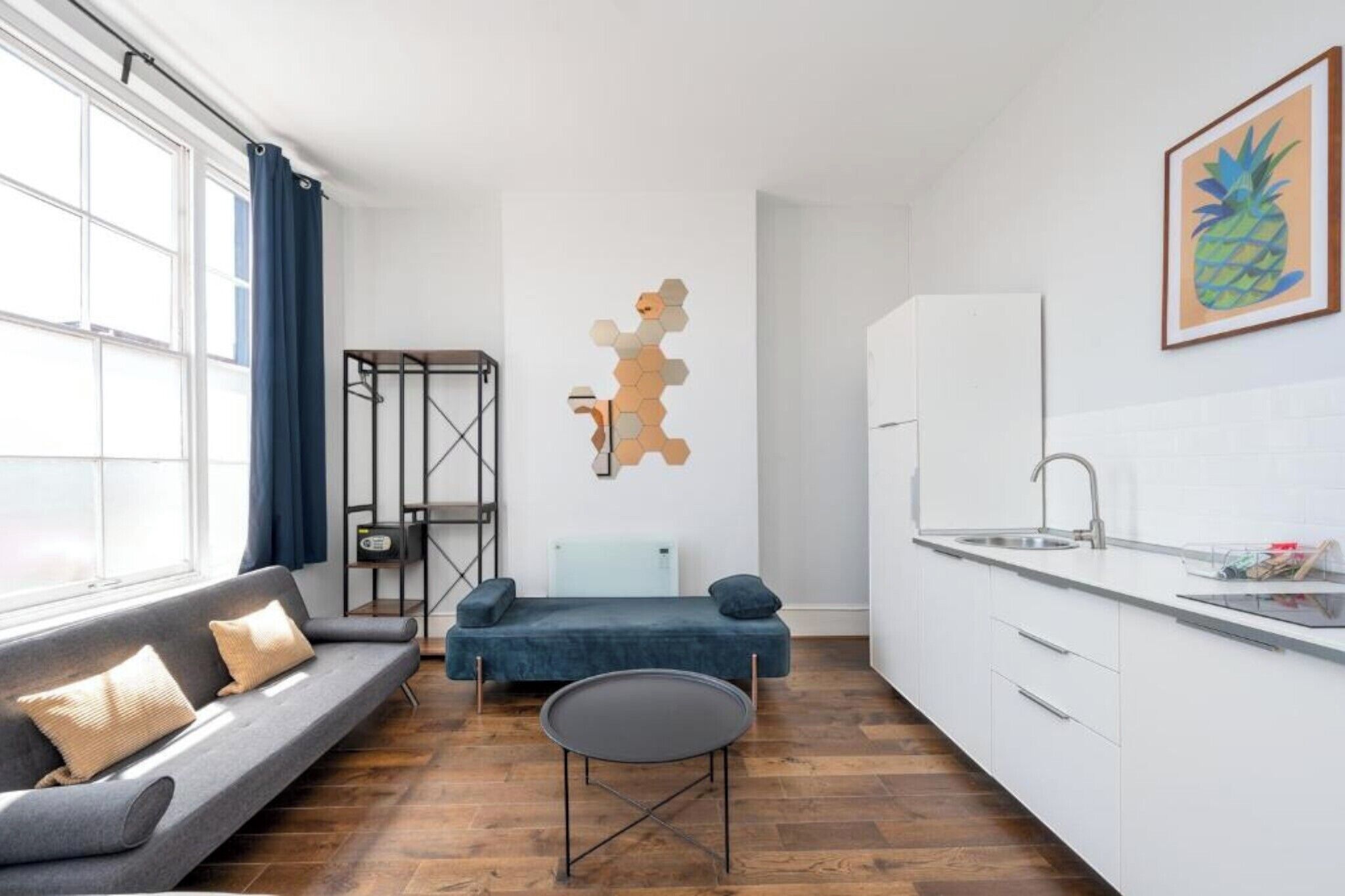 A modern kitchen with a white countertop, a built-in sink, and a window with blue curtains.