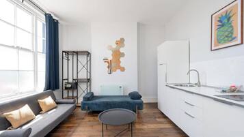 A modern kitchen with a white countertop, a built-in sink, and a window with blue curtains.
