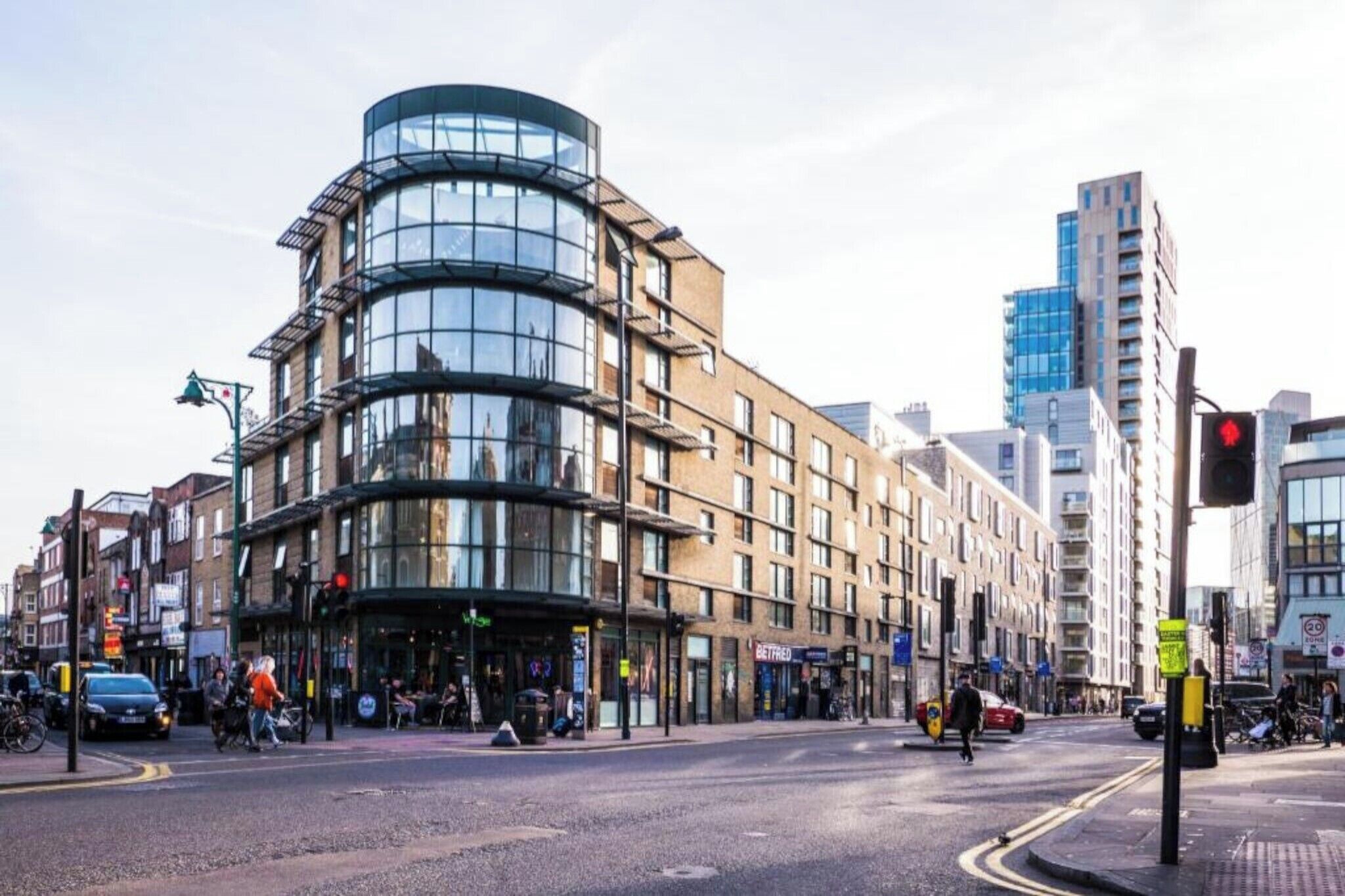 A modern building with a curved glass facade, a pedestrian crossing, and a traffic light.