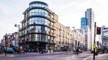 A modern building with a curved glass facade, a pedestrian crossing, and a traffic light.