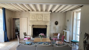 A spacious living room with a fireplace, a sofa, chairs, and a dining table. - Chateau à 20 min du circuit des 24H (Soulitré)