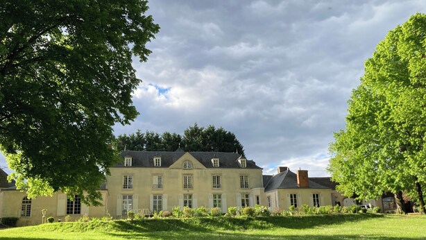 A large, multi-story building with a symmetrical facade, multiple windows, and a well-maintained lawn in front. - Chateau à 20 min du circuit des 24H (Soulitré)