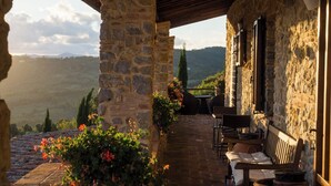 A stone building with a covered patio, stone pillars, and outdoor seating. - Poggio alla Rocca (Civitella Paganico)