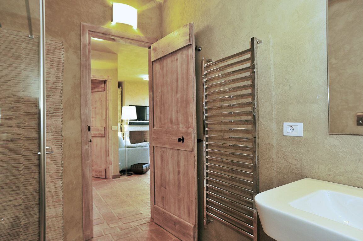 Un baño con lavamanos, perchero para toallas y puerta de madera.