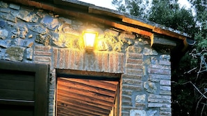 Un edificio rustico in pietra con una porta in legno, una piccola scalinata che conduce a un portico e un cartello con scritto 'Alba'.
