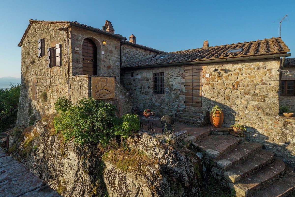 Un edificio de piedra con aspecto rústico, que presenta un pequeño porche y una escalera hacia la entrada.