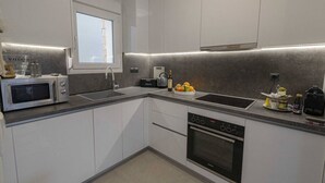 A modern kitchen with a built-in microwave, oven, and sink. - Villa Magdalena by RentalsPro - Nikiti Halkidiki (Νικήτη)