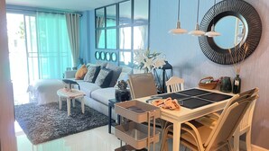 Una sala de estar moderna con sofá, mesa de comedor, sillas y un espejo grande.