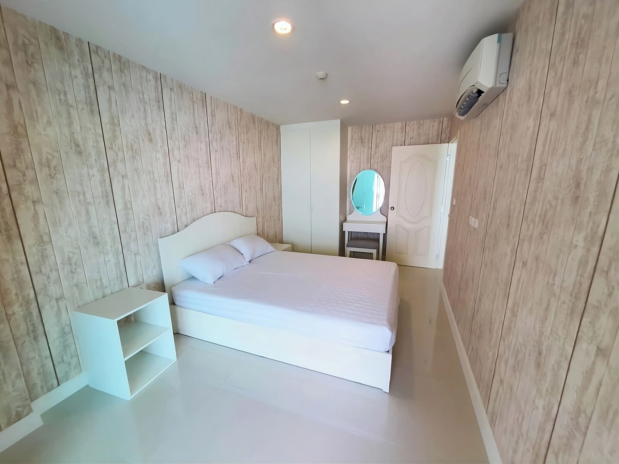 Ein Schlafzimmer mit Bett, Nachttisch, Spiegel und Kleiderschrank.