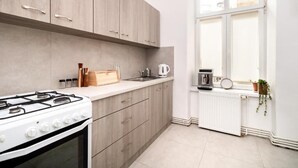 Eine moderne Küche mit Gasherd, Holzschränken, einem Fenster mit Blick und einer weißen Arbeitsplatte.