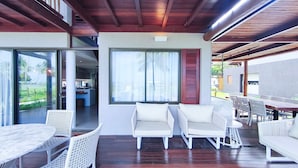 A covered outdoor area with a dining table, chairs, and a view of a kitchen and pool. - Bangalo no Carneiros Atlantico by CTA (Tamandaré)
