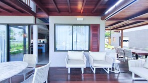 Un espacio al aire libre techado con una mesa, sillas y vistas a una cocina y una piscina.