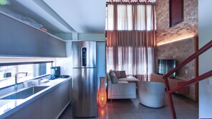 A modern kitchen with a built-in refrigerator, a coffee machine, and a window overlooking a balcony. - Bangalo no Carneiros Atlantico by CTA (Tamandaré)