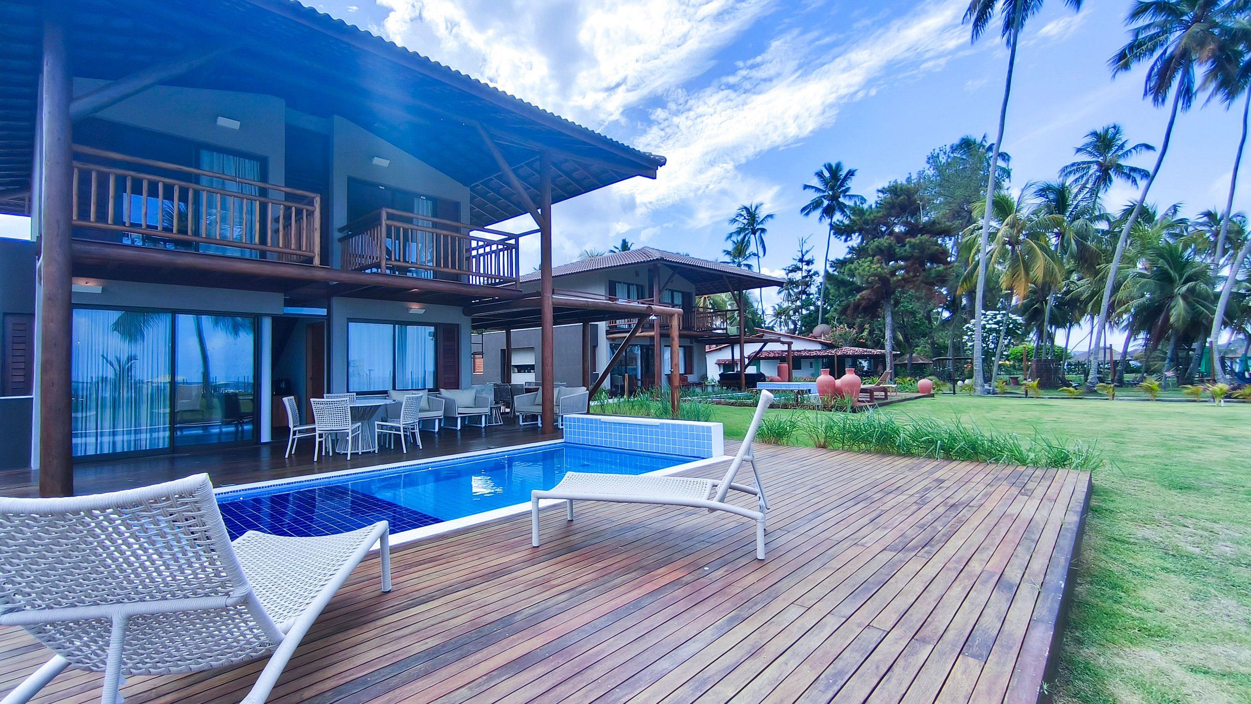 A resort with a pool, outdoor seating, and a view of palm trees.