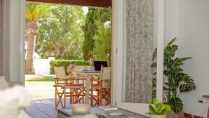 Une pièce comprenant un coin repas, une petite table avec des chaises, un ordinateur portable et une plante en pot.