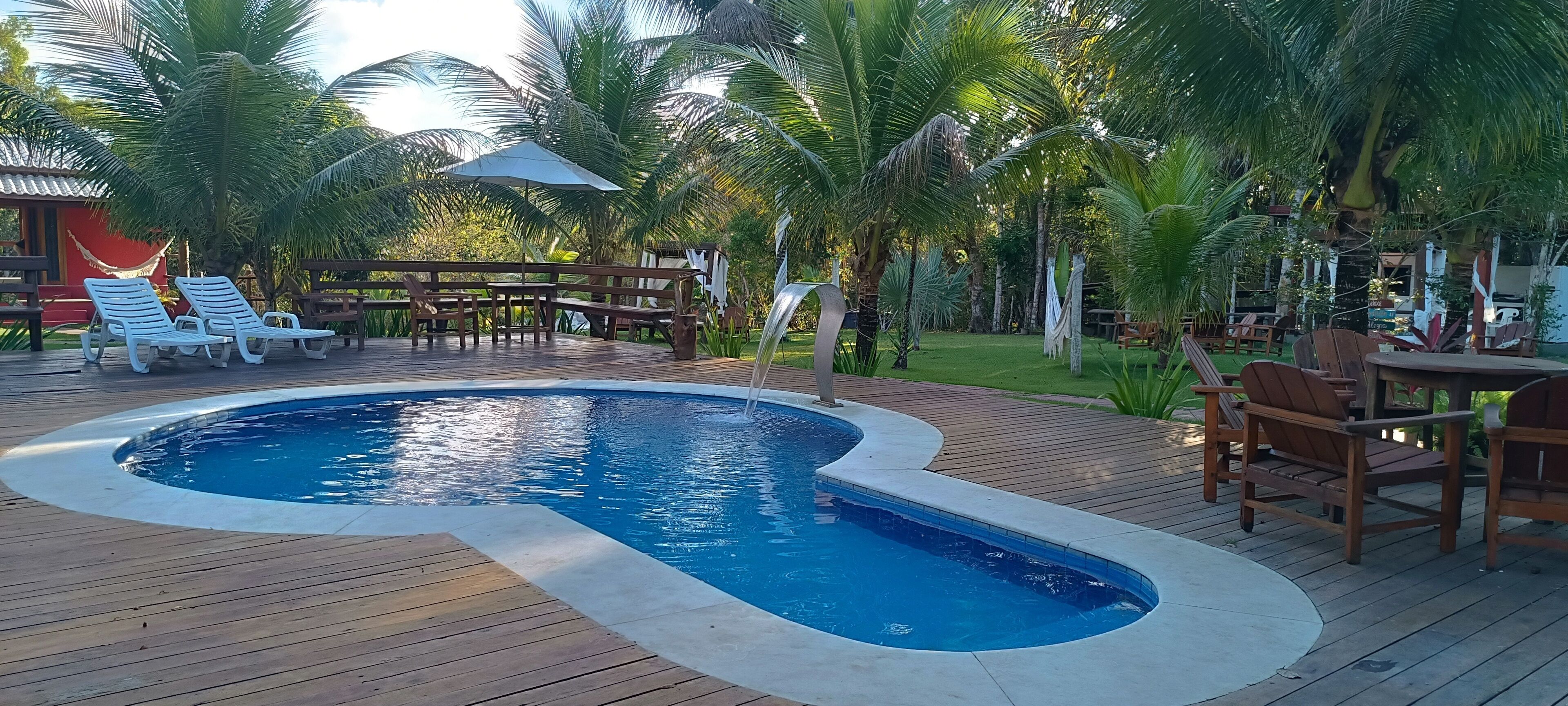 A pool with lounge chairs, wooden deck, and palm trees.