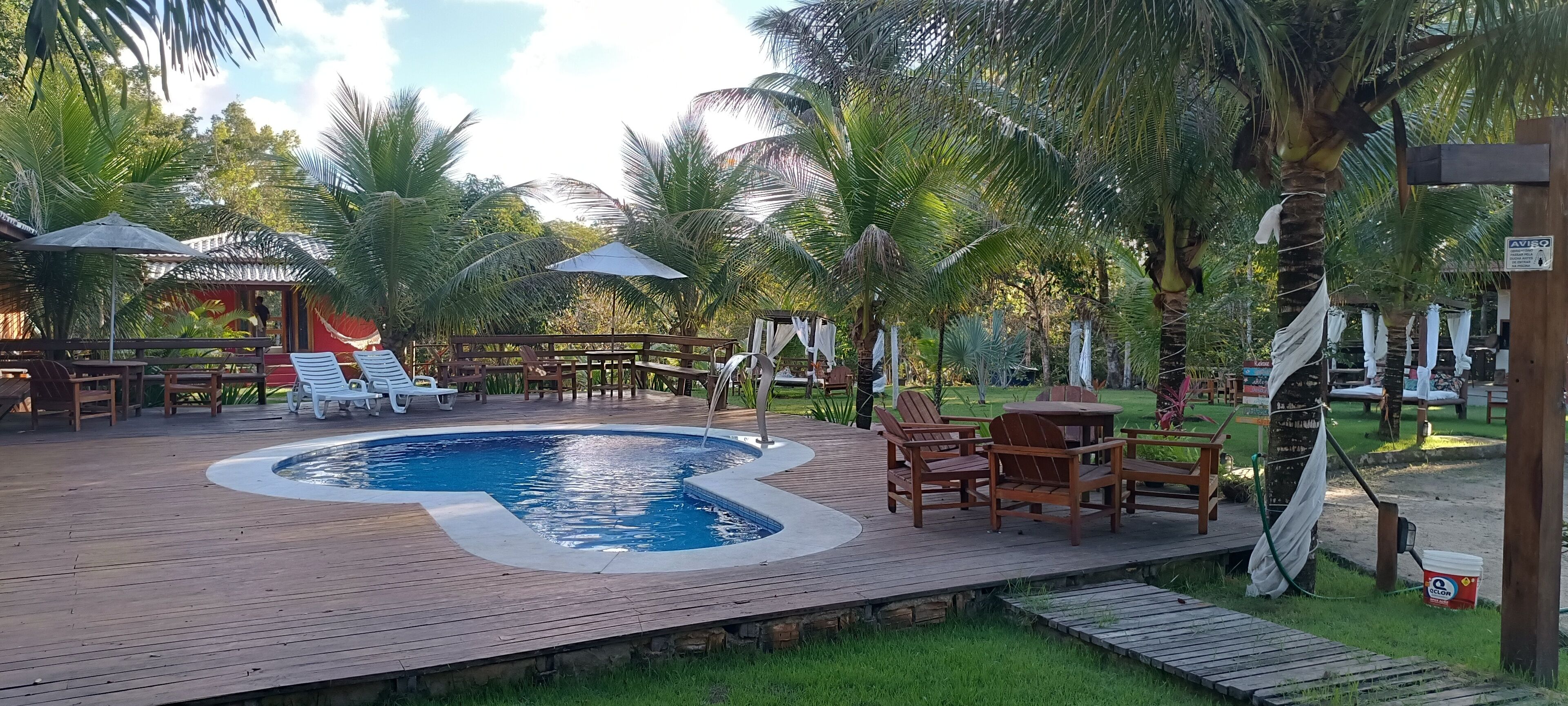 A wooden deck with a swimming pool, lounge chairs, and a small table.