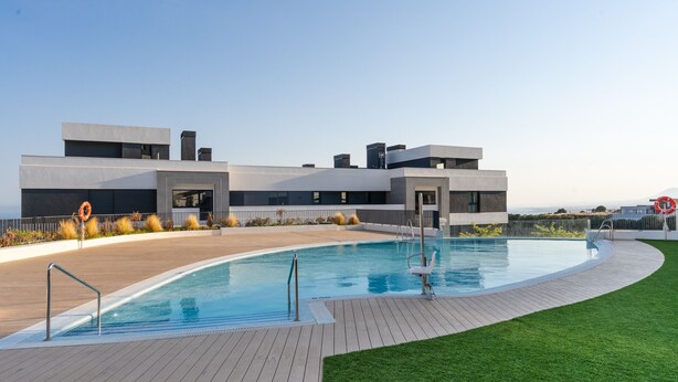 Een modern gebouw met een zwembad, terras en gazon.
