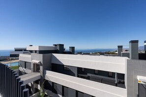 A modern building with a rooftop terrace overlooking a body of water. - Med Blue by Time& Home (Marbella)