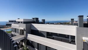 Een modern gebouw met balkons, een zwembad en uitzicht op zee.