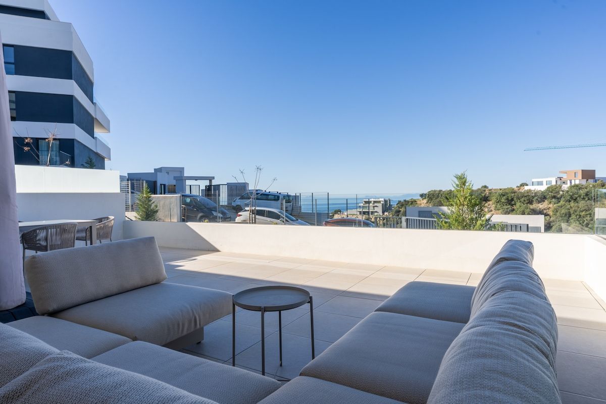 Una terraza en la azotea con un conjunto de sofás, una mesita redonda y vistas de la ciudad.